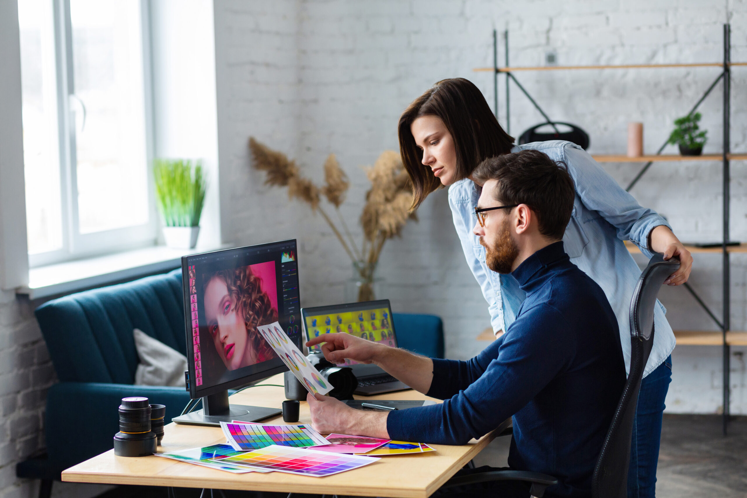Deux personnes d'une agence de publicité travaillent en regardant un ordinateur sur lequel on voit la future image d'une publicité